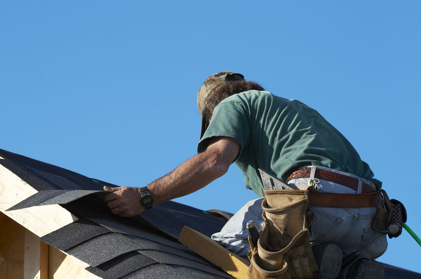 guy working on roof replacing shingles